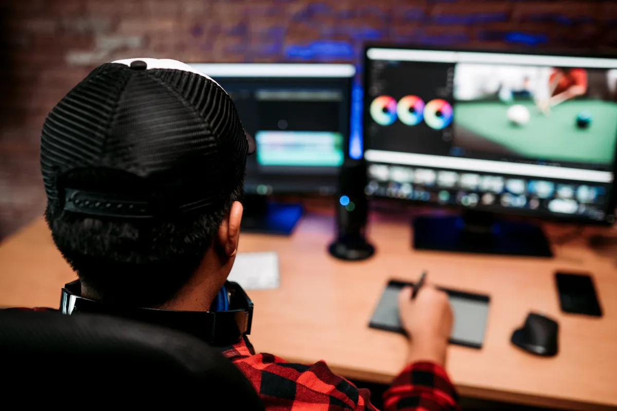 Montatore video al lavoro su due monitor mentre prepara i sottotitoli