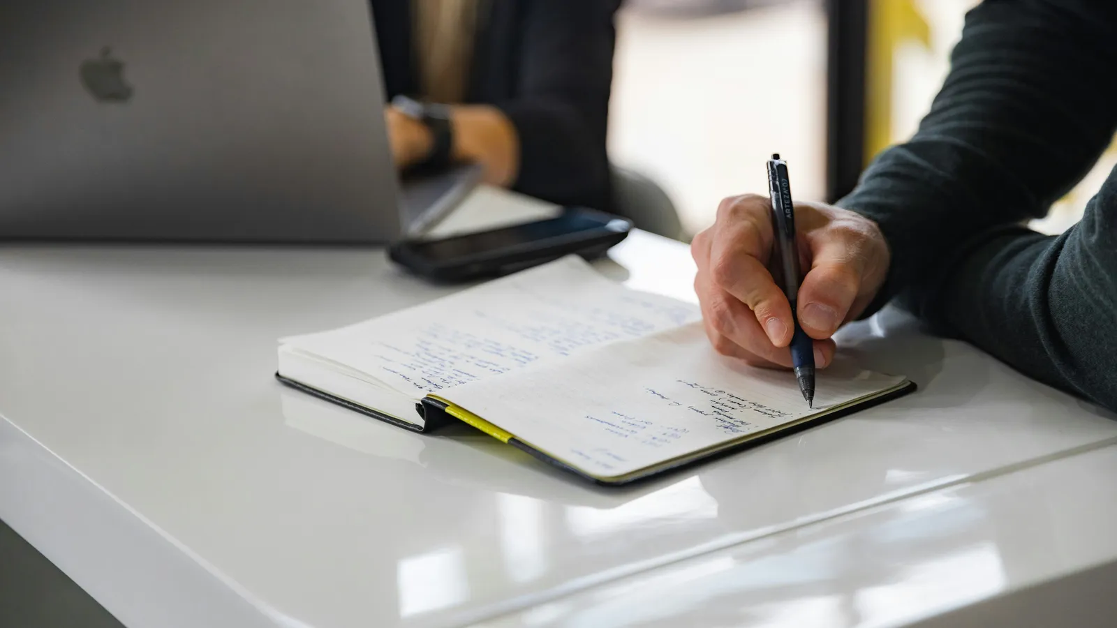 Hand writing notes on paper, representing consecutive note-taking