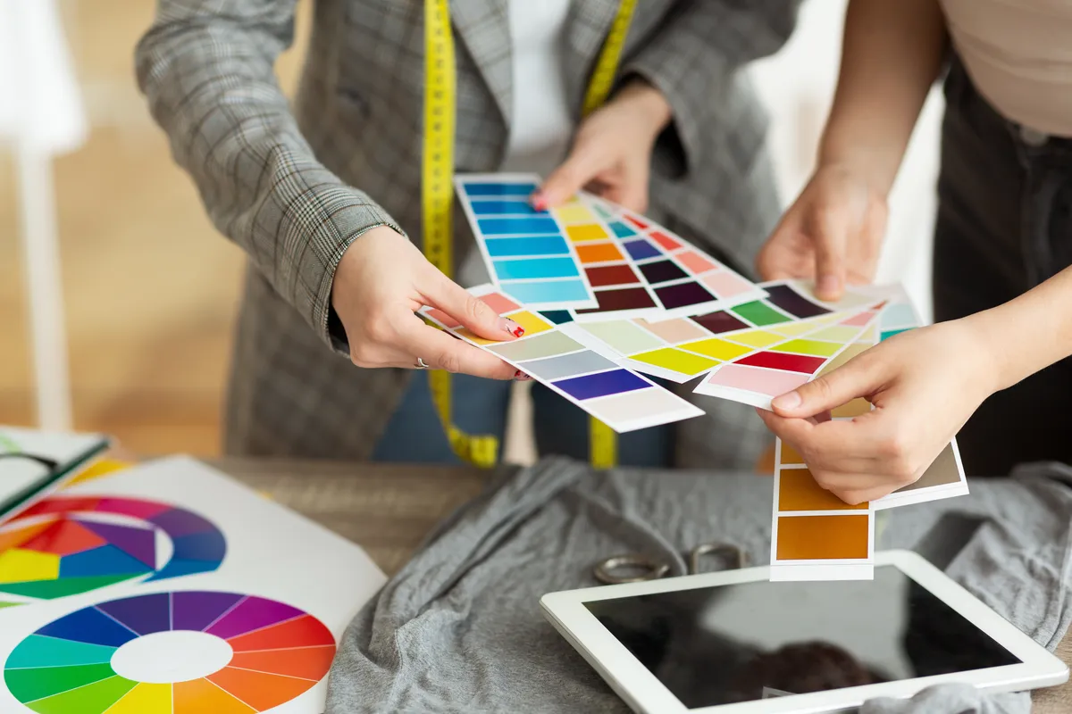 Fashion designers comparing colour swatches and textile samples on a worktable