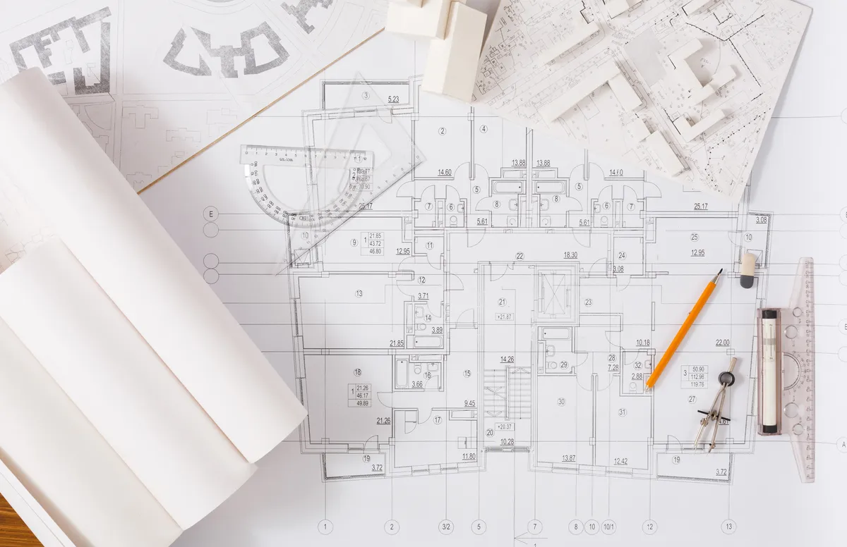 Engineering blueprints with a drafting compass and technical drawings on a desk