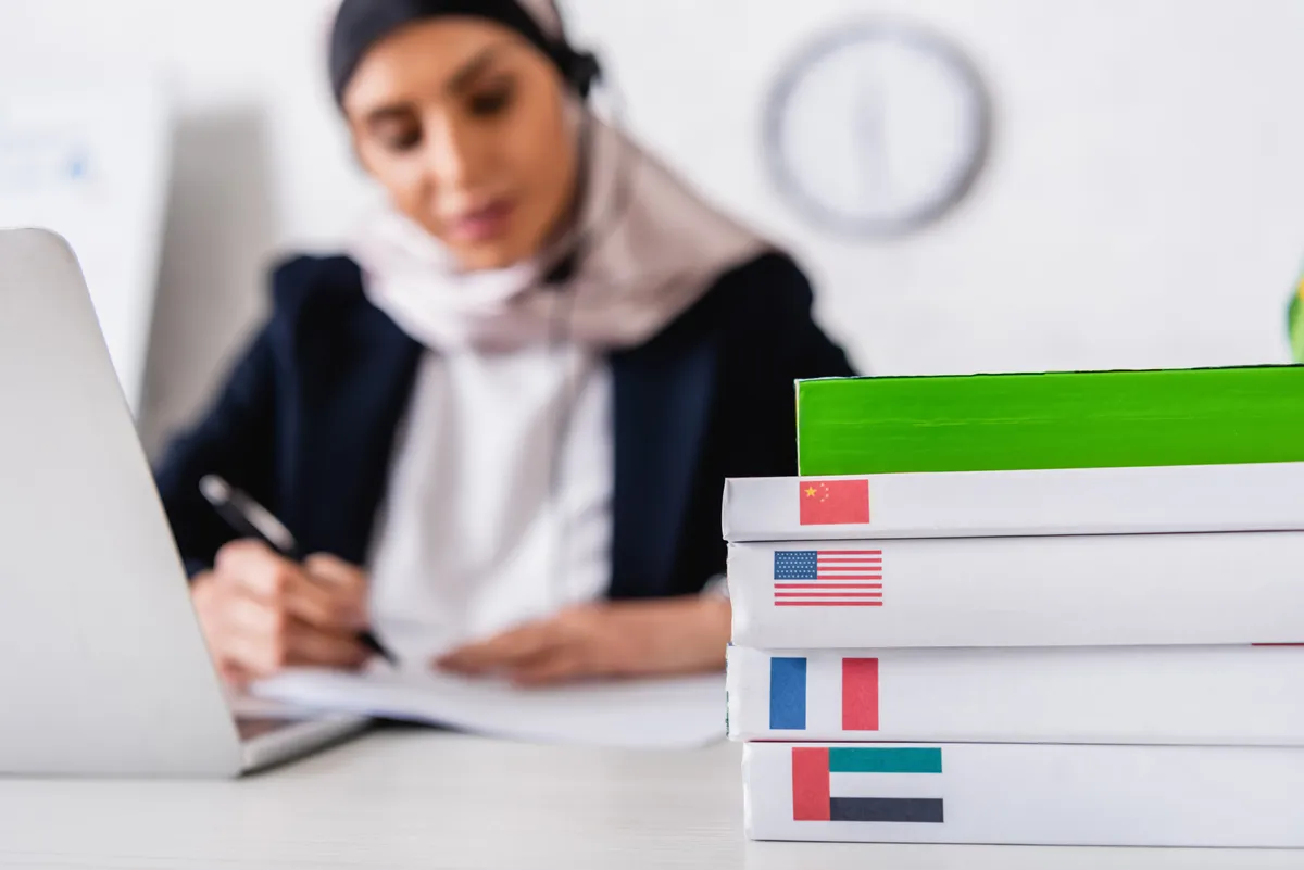 Translator at work surrounded by foreign-language dictionaries and reference materials