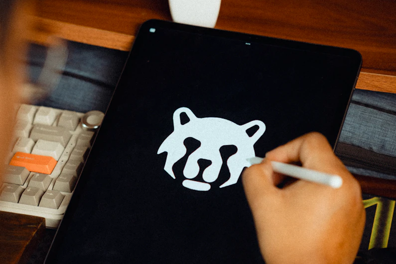A designer sketching a simple animal-mark logo by hand on a tablet