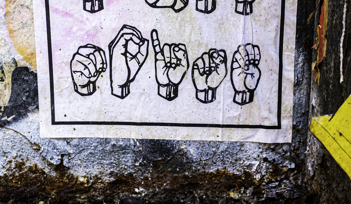 A weathered poster of illustrated hands demonstrating American Sign Language finger-spelling