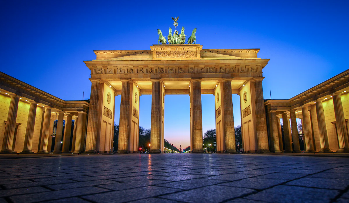 The Brandenburg Gate illuminated at dusk against a clear blue sky in Berlin