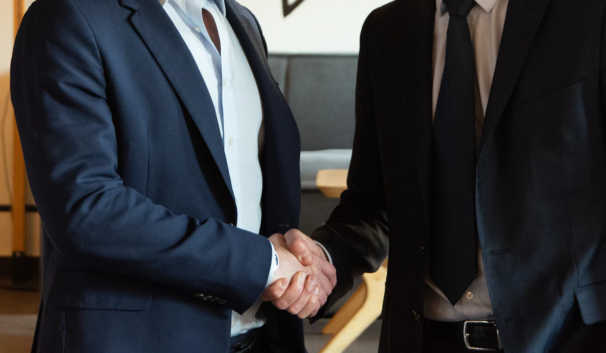 Two businessmen in suits shaking hands to close a deal