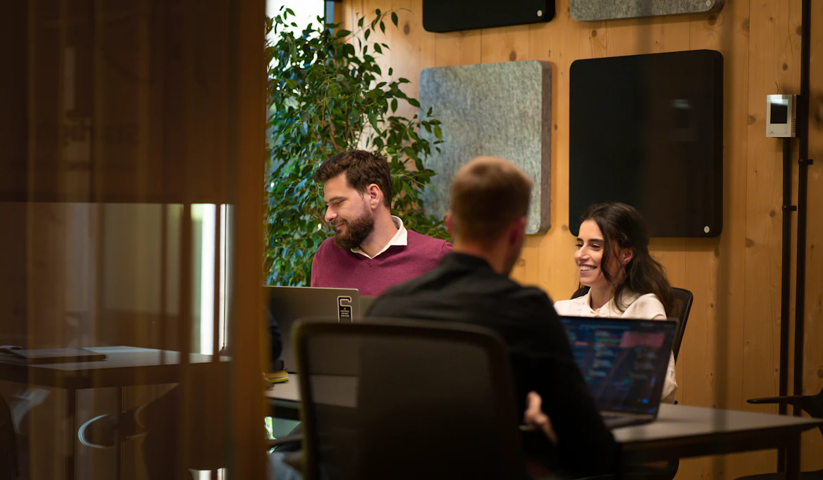 Colleagues talking and working on laptops in a modern coworking meeting room