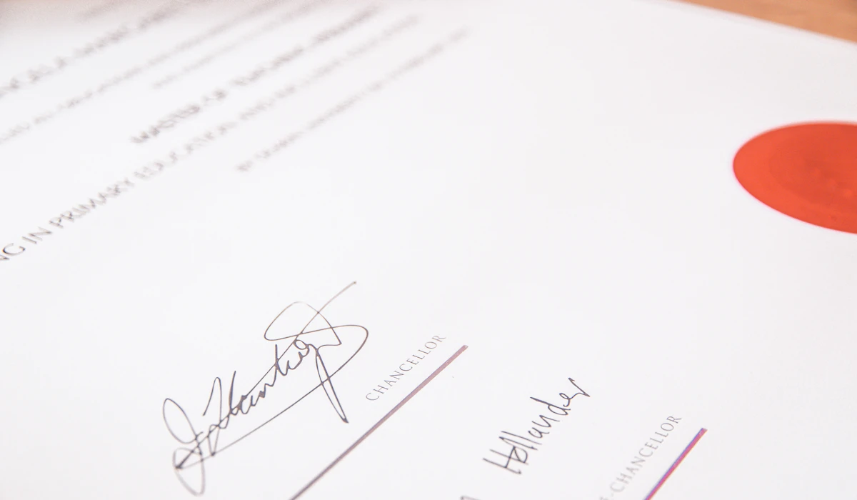 A close-up of a signed certificate with a red wax-style seal