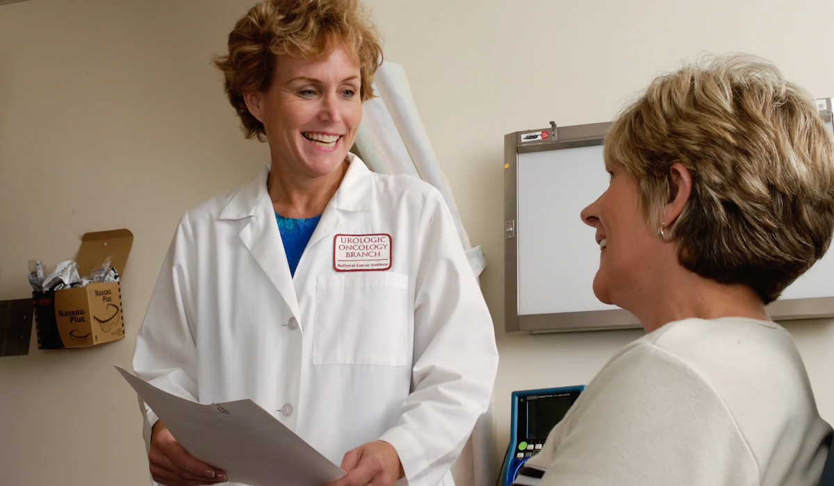 A smiling doctor in a white coat talking with a patient in a clinic