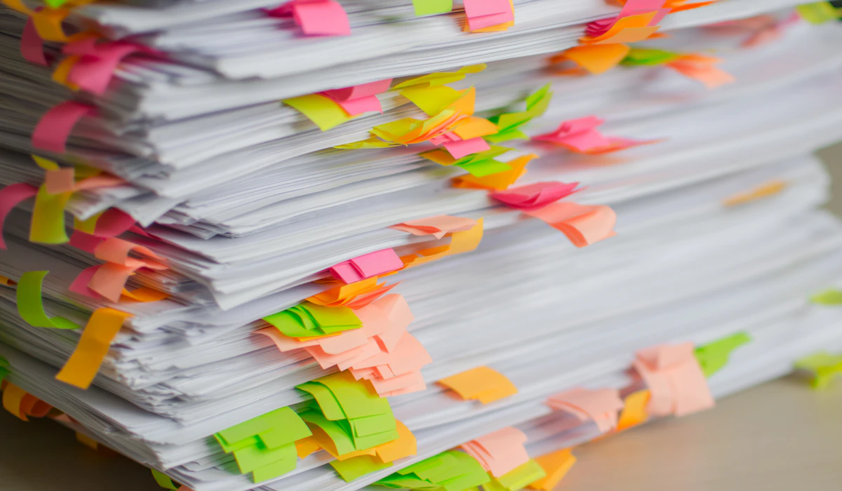 Two tall stacks of printed documents, almost every page flagged with a coloured sticky tab