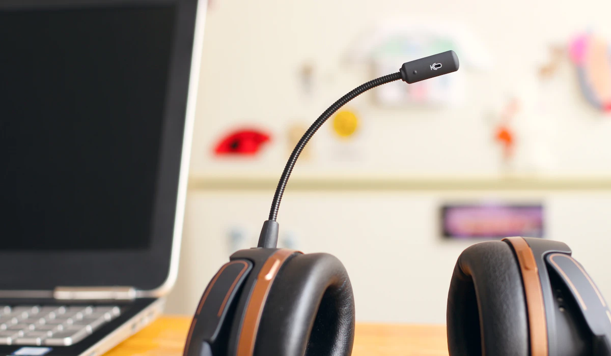 A headset with a boom microphone resting beside an open laptop