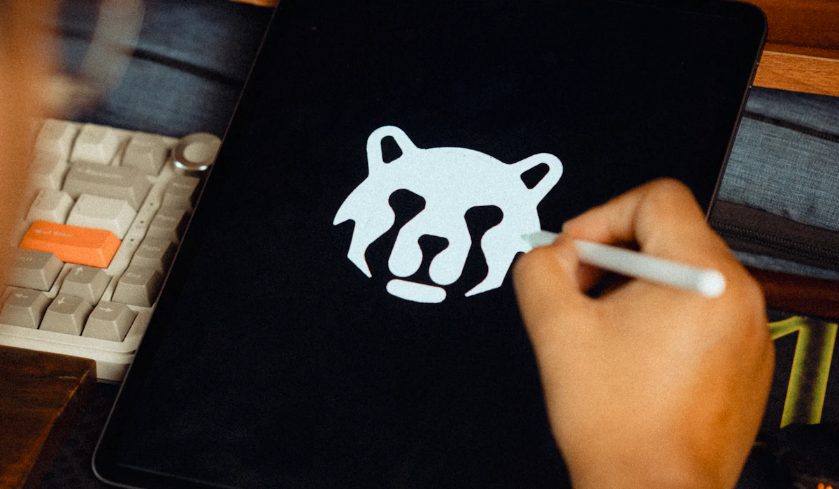 A hand sketching a logo design on a tablet with a stylus