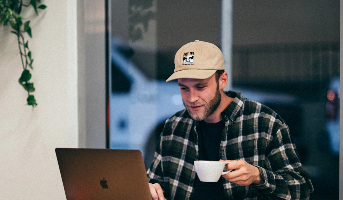 A man drinking coffee while working on a laptop in a cafe