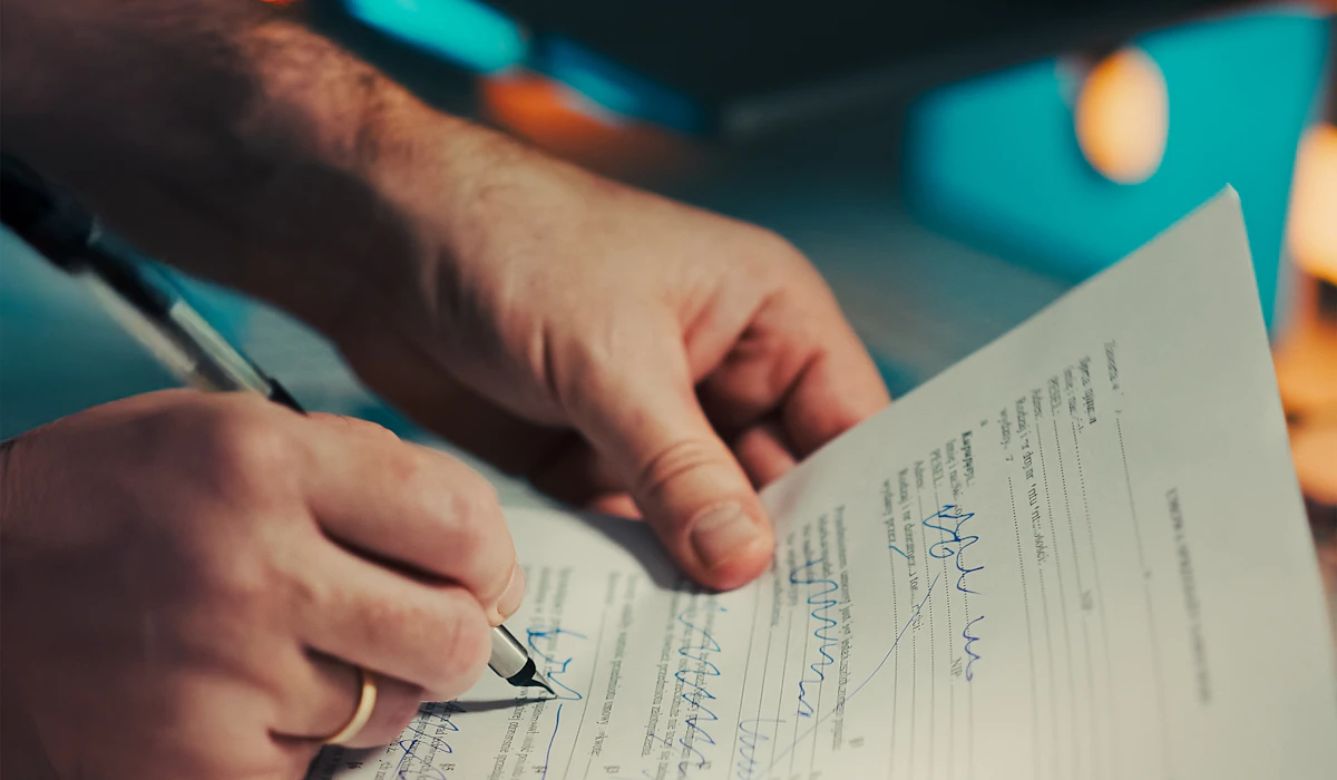 Un uomo firma un documento con una penna stilografica