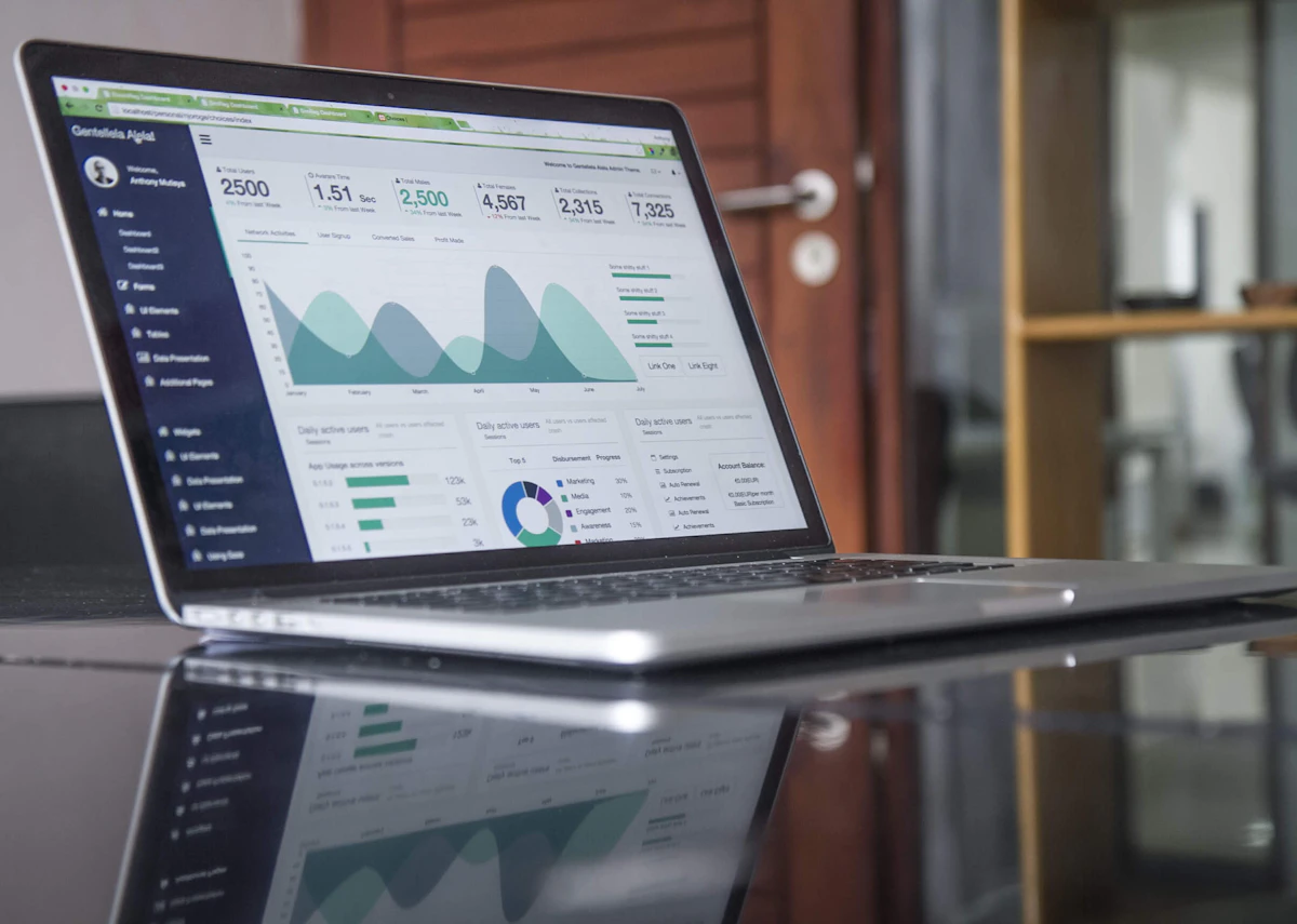 A laptop on a desk showing a marketing analytics dashboard with charts and user counts