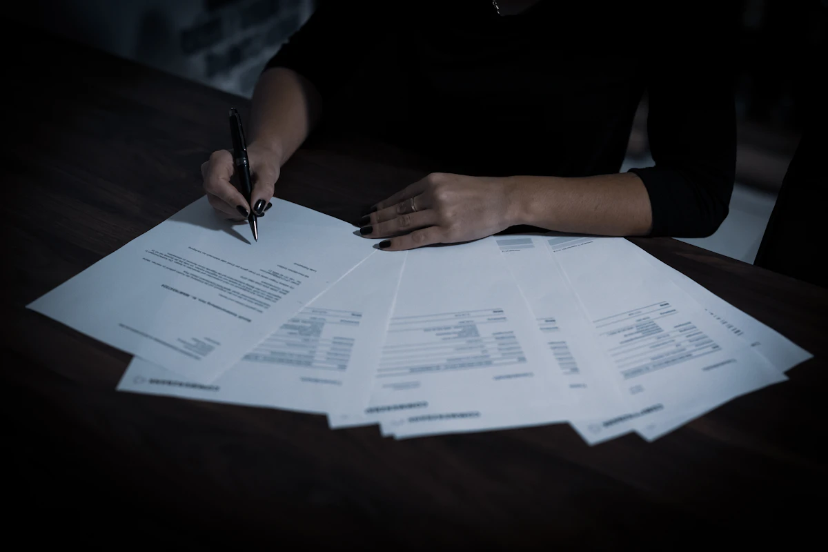 A person reviewing a fan of printed documents with a pen