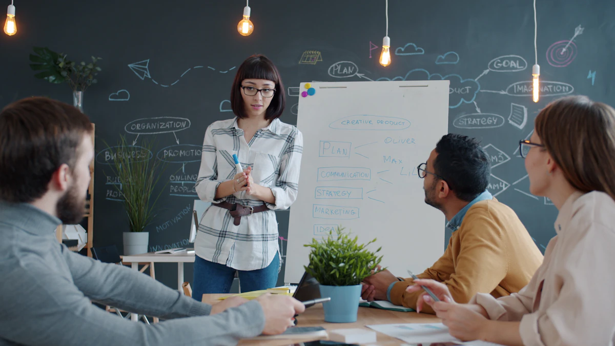 A woman presenting at a flipchart beside a chalkboard wall covered in strategy diagrams, with three colleagues listening around a table