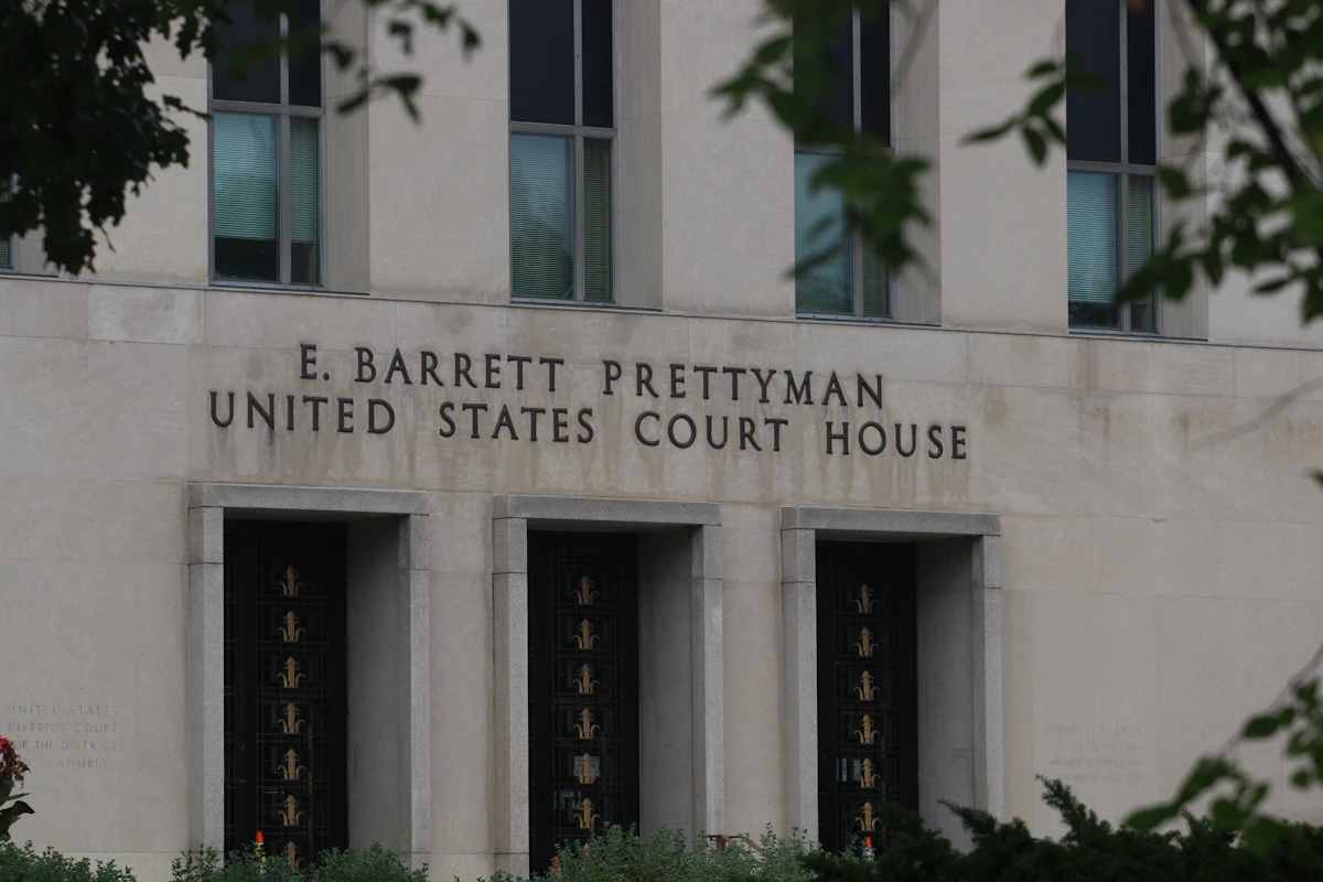 The stone facade of the E. Barrett Prettyman United States Court House in Washington DC, seen through tree branches